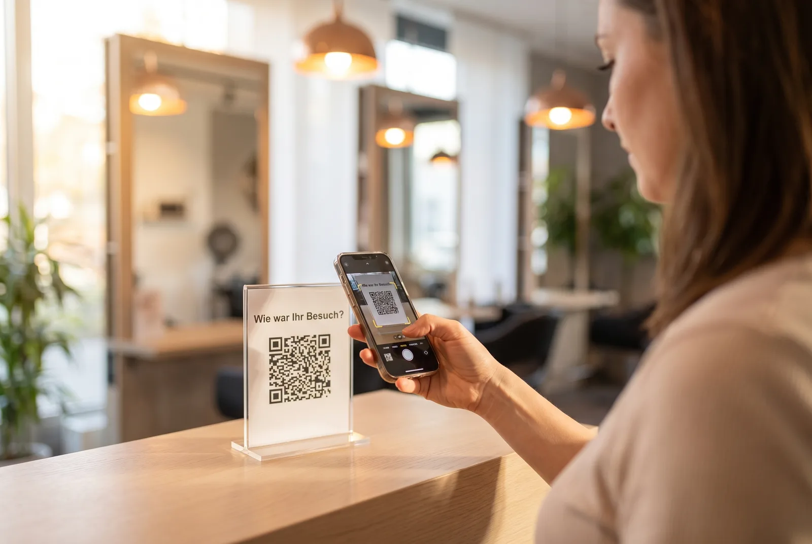 Kundin scannt an der Theke eines Friseursalons den QR-Code auf einem Acryl-Aufsteller